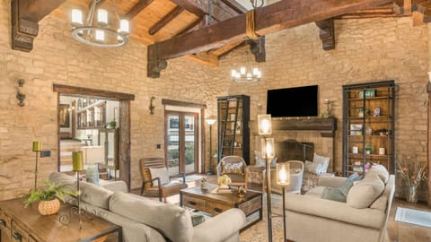 Grand living room framed by stone walls, exposed beams, and a cozy fireplace—designed for relaxed gatherings and fireside evenings.