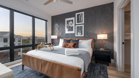 Spacious primary bedroom with a designer accent wall and large floor-to-ceiling windows.