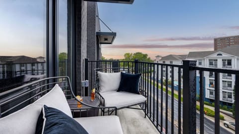 Private balcony with comfortable outdoor seating and sunset views over the city.