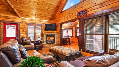 Main living area featuring vaulted ceilings, a stone fireplace, and rustic decor.