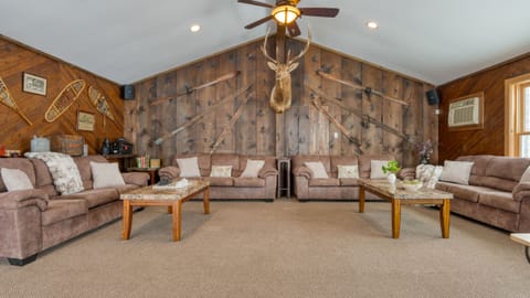 Expansive living room with ample seating, pool view, TV, and a fireplace.