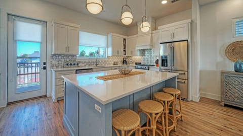 Modern kitchen with a large blue island, white cabinetry, and pendant lighting.