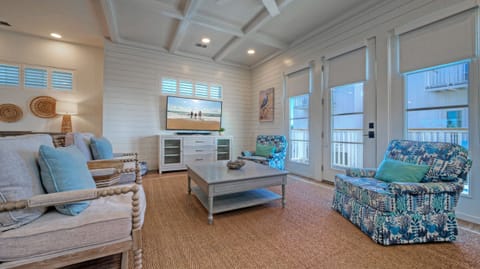 Spacious living room featuring coastal decor, white shiplap walls, and balcony access.