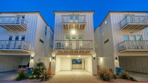 Front exterior of the three-story home at twilight, showing the carport and balconies.