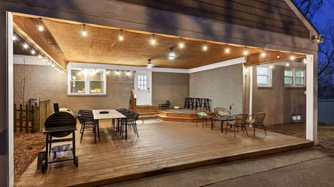 Covered outdoor deck with dining, lounge seating, string lights, and grill.