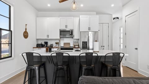 Modern kitchen featuring white cabinetry, dark island, and industrial bar stools.