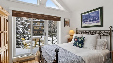 Sun-drenched studio bedroom featuring vaulted ceilings and a private balcony with snowy views.