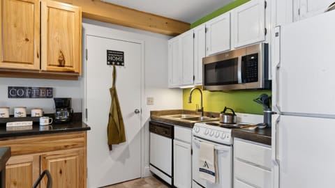 Fully equipped kitchen with white appliances and a green accent wall.