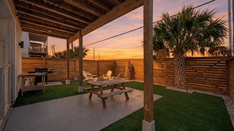 Shaded outdoor dining area with grill and fenced yard for easy cookouts.