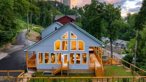 Warm sunset glow over this modern mountain home, featuring expansive windows, wraparound decks, and a peaceful wooded hillside setting. (Perfect Too)