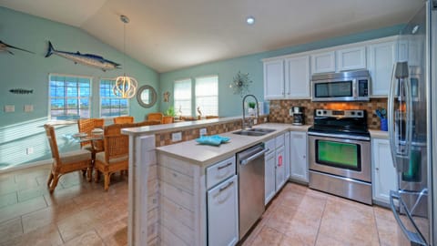 Kitchen area with white cabinetry, stainless steel appliances, and a breakfast bar.