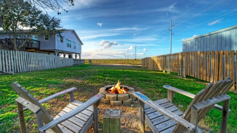 Backyard fire pit area with wooden Adirondack chairs and a fenced lawn.