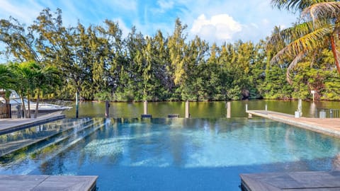 Serene waterfront pool deck overlooking calm waters and lush tropical views.