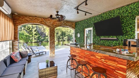 Converted garage hangout with a covered bar, lounge seating, and TV.