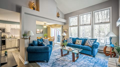 A bright, open living space with vaulted ceilings, forest views, and cozy seating—perfect for gathering after a day in the Poconos.