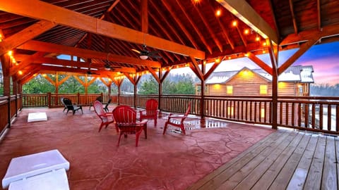 Expansive covered pavilion with string lights, ceiling fans, and ample seating—an inviting space for evening gatherings, games, and mountain air views.