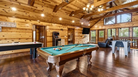 Spacious game loft with vaulted wood ceilings, air hockey, pool table, arcade games, and a built-in putting green for friendly competitions and laid-back fun.