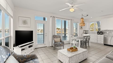 Bright first-floor living room with an open layout, comfortable seating, and large windows that bring in natural light and calming water views.