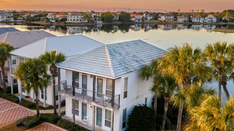 Aerial view of this waterfront community, showcasing palm-lined buildings, serene lake views, and easy access to the beach and resort-style amenities nearby.