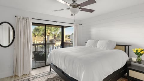 Bright bedroom with a ceiling fan and sliding doors leading to a private balcony.