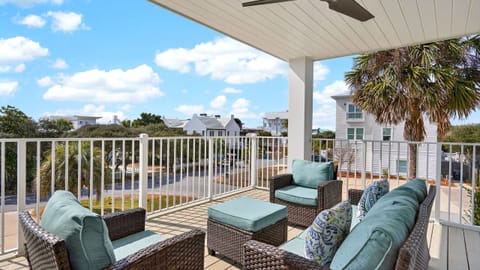 Shaded balcony lounge with a ceiling fan—sip coffee, catch the breeze, and enjoy easy coastal views over the neighborhood.