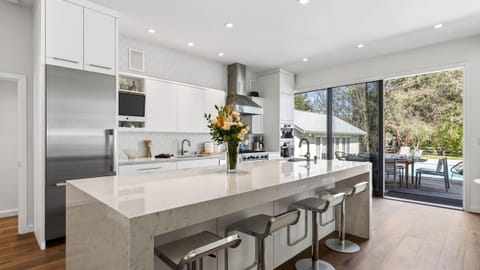 Bright, modern kitchen with waterfall island, premium appliances, and seamless indoor-outdoor flow to the pool deck.