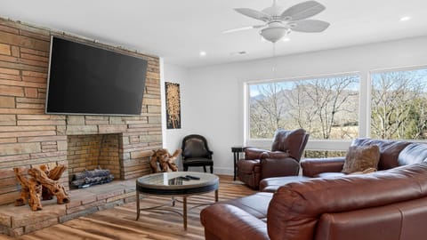 Cozy mountain-view living room with a stone fireplace, plush seating, and big-screen TV.