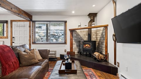 Cozy living room with a wood-burning stove, plush leather seating, and a big-screen TV—perfect for après-ski nights.
