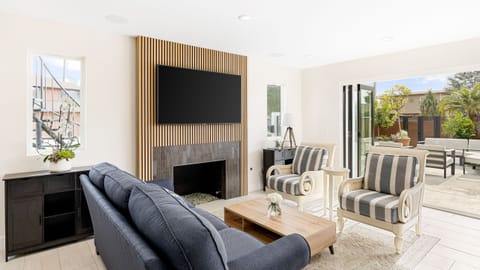 Living Room with blue sofa facing a wood-paneled accent wall with a mounted TV and fireplace.