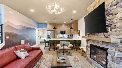 Gather by the stone fireplace—huge TV, cozy seating, and a warm lodge-style vibe.