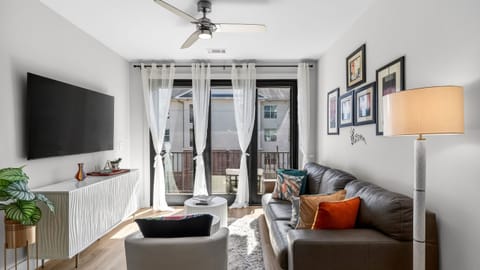 Sunlit living room with balcony access + smart TV.