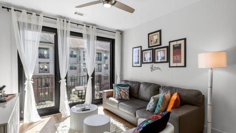 Bright, airy living room with floor-to-ceiling windows, comfy seating, and balcony access.