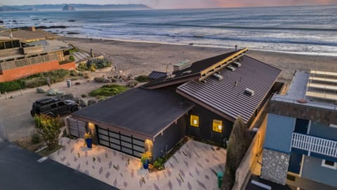 An elevated dusk view of the modern beachfront home with a view of the shoreline.