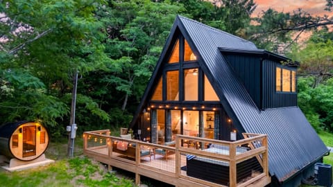 Vaulted A-frame living with wall-to-wall windows and seamless deck access—your private woodland view, all day long.