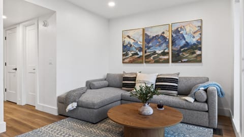 Cozy, modern living area with a plush sectional, warm wood accents, and mountain-inspired artwork—your perfect spot to unwind after a day on the slopes.