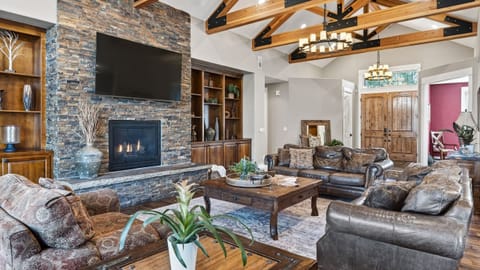 Timber beams, a grand stone fireplace, and plenty of space to gather—your cozy lodge-style living room awaits.