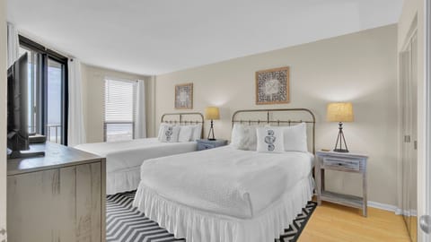 Two queen beds with white bedding and a patterned rug.