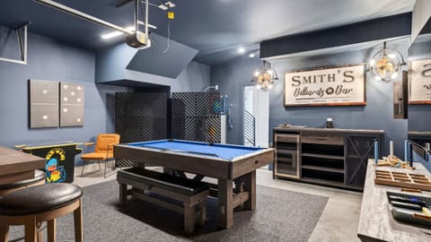 The game room is designed for all-ages fun with a pool table, arcade game, and bar area for laid-back nights in.