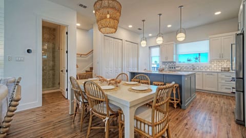 Dining area with a large wooden table, wicker chairs, and a statement chandelier. (Southern Cross)