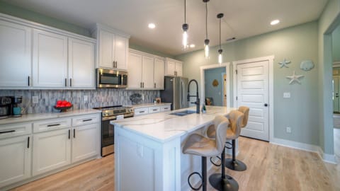 The bright kitchen features a large island, bar seating, and plenty of space for easy meals together.