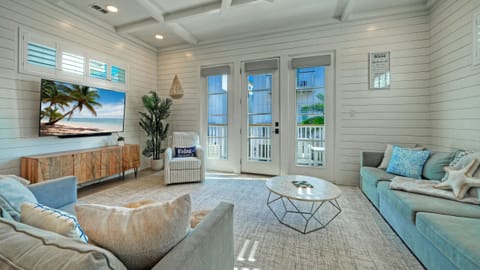 Bright living room with coastal decor, white shiplap walls, and balcony access. (Villa Blanca)