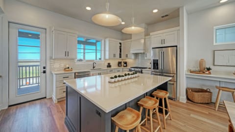 Fully equipped kitchen with large island, barstool seating, and reliable equipment. (Dune & Done)