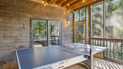 Screened game porch with ping pong and string lights.