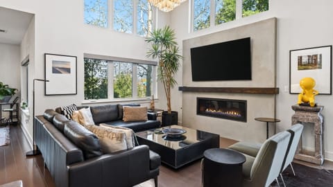 Spacious living room with soaring ceilings, oversized windows, and a sleek fireplace that anchors the space.