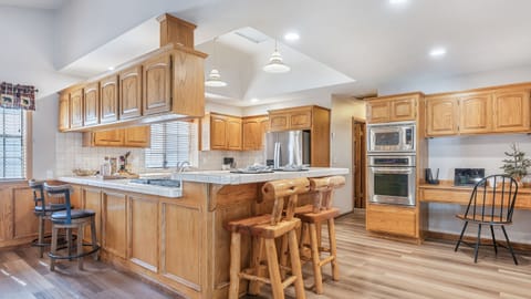 Spacious cabin-style kitchen with a large island, rustic log barstools, and stainless steel appliances—perfect for gathering and cooking together.