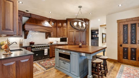 A warm, inviting living room with a fireplace and tall windows overlooking the trees.