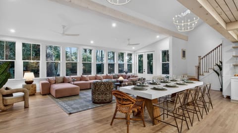 Airy open‑concept living and dining area with tall windows and warm modern design.