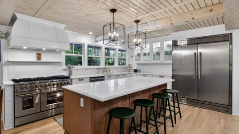Bright modern kitchen with a marble island, brass accents, and warm wood details.