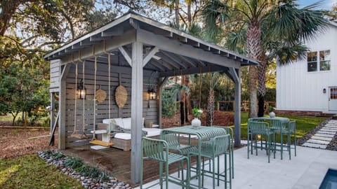 Relaxed pergola lounge with cozy seating, rope swings, and lush tropical surroundings.