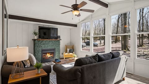 Warm and inviting living room featuring a stone fireplace and large windows.